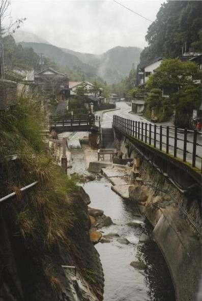 Misty onsen town street in the mountains of Japan with traditional ryokan buildings